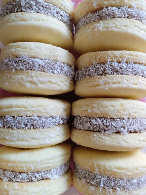 Alfajores de maicena rellenos de dulce de leche con los bordes en coco